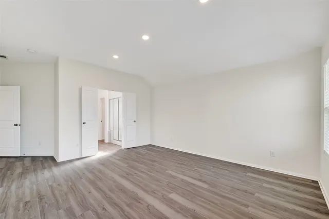 a view of an empty room with wooden floor and closet