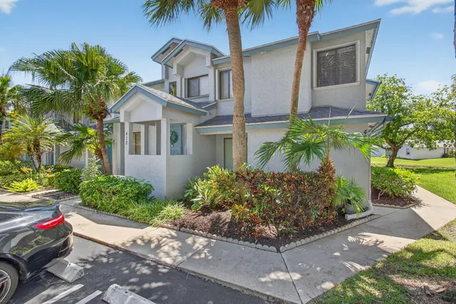 a front view of a house with a yard and potted plants