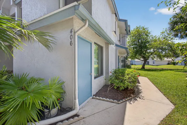a front view of a house with a yard and potted plants