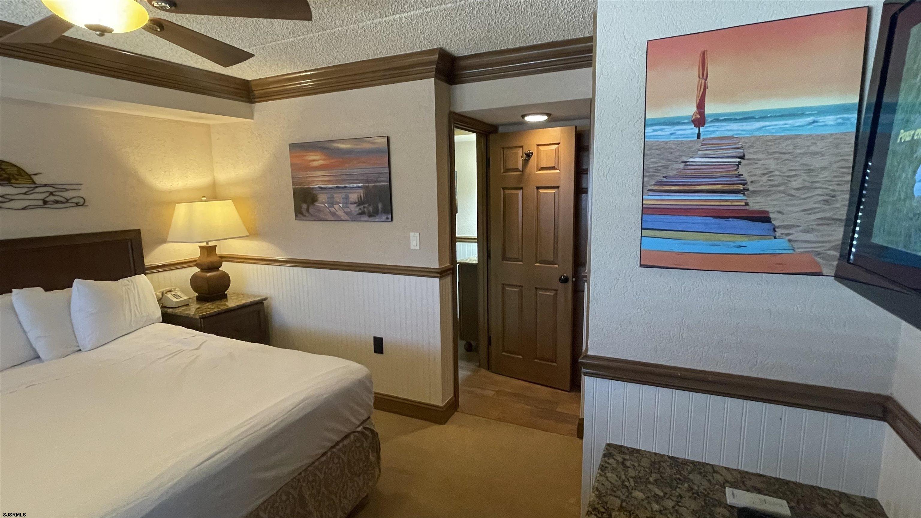 820 Ocean Avenue, Unit 115 Ocean City, NJ 08226 - Photo 26 of 58 a bedroom with a bed and a lamp on the dresser