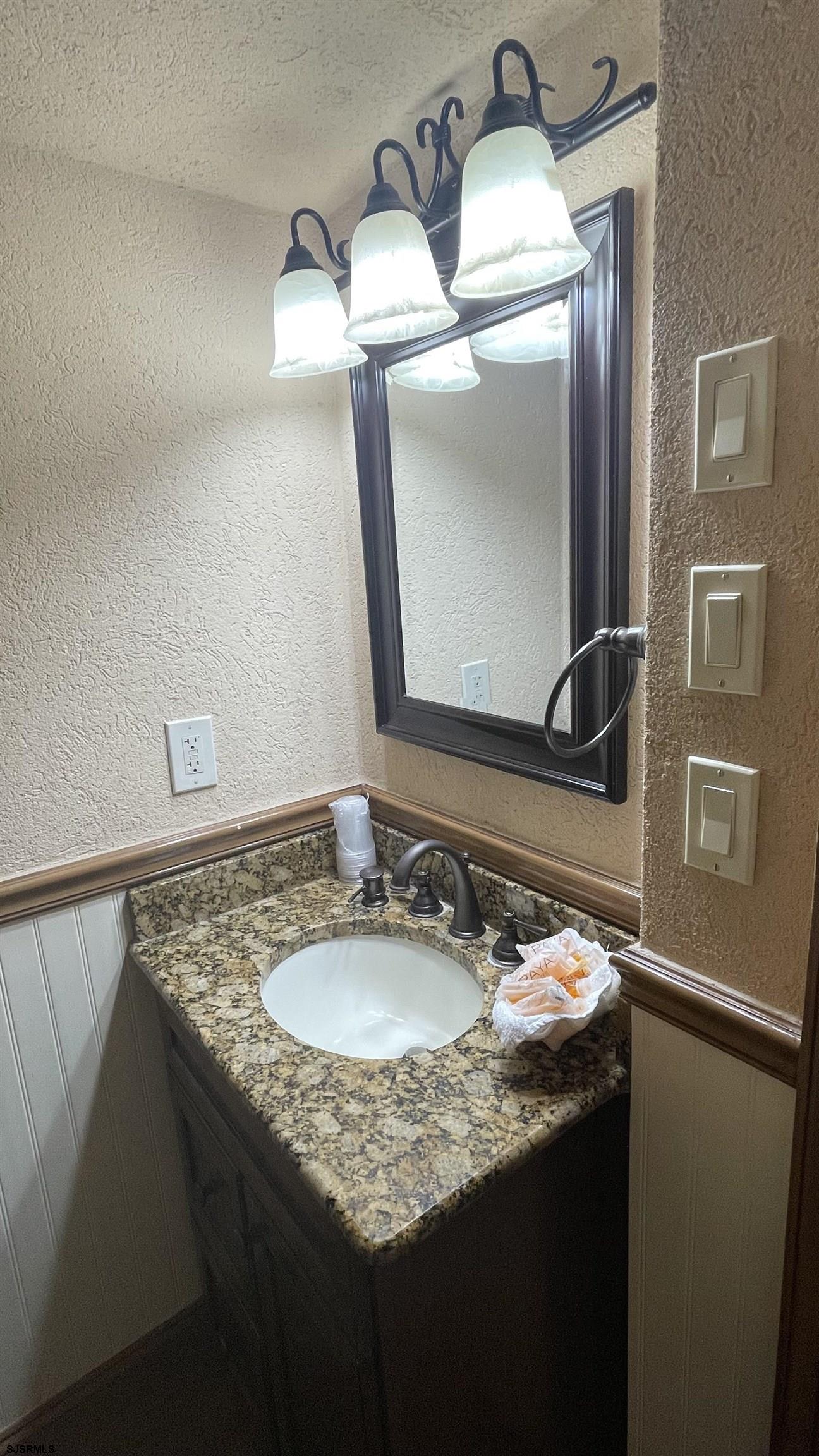 820 Ocean Avenue, Unit 115 Ocean City, NJ 08226 - Photo 32 of 58 a bathroom with a granite countertop sink and a mirror