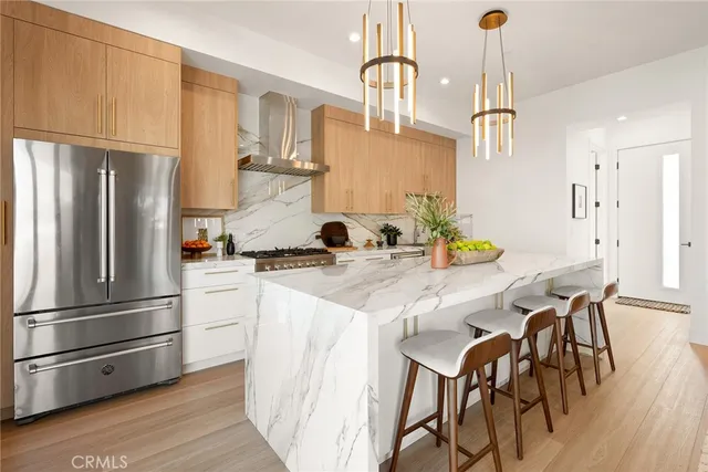 a kitchen with stainless steel appliances granite countertop a refrigerator a sink dishwasher a stove and a refrigerator with wooden floor