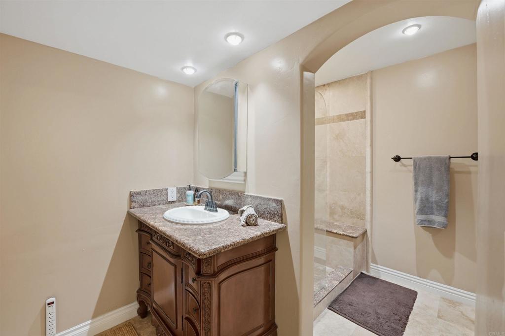 2414 Sacada Circle Carlsbad, CA 92009 - Photo 31 of 56 a bathroom with a granite countertop sink a mirror and a shower