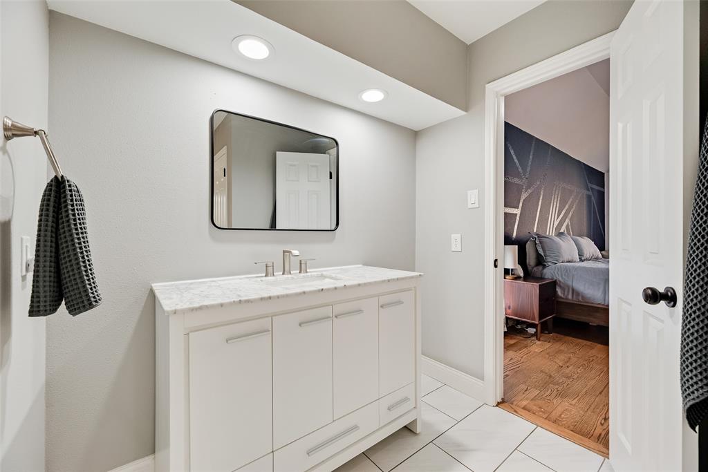 740 Newport Road Fort Worth, TX 76120 - Photo 25 of 38 a en suite bathroom with a granite countertop sink and a mirror