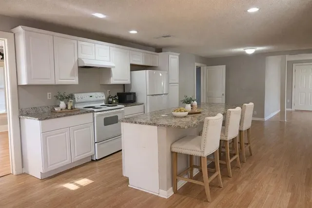 a kitchen with granite countertop white cabinets and stainless steel appliances