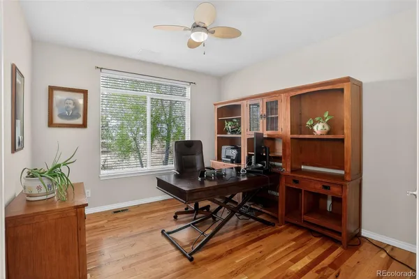 a view of a hallway to a room with wooden floor and windows