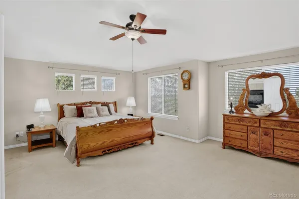 a spacious bedroom with a bed a chandelier and a mirror on dresser