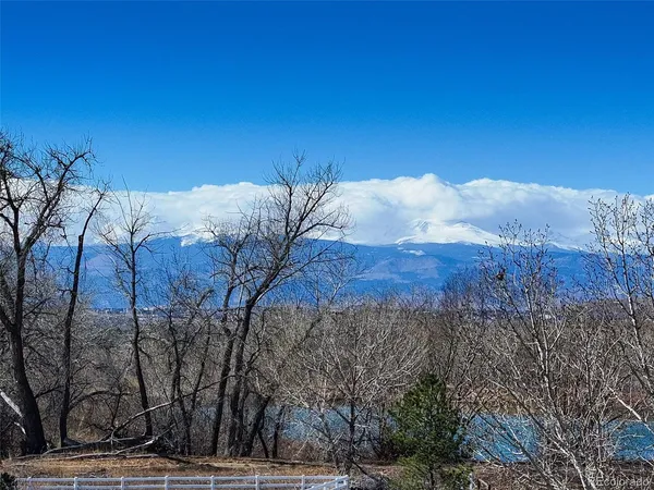 a view of a white house with a yard covered with snow and trees