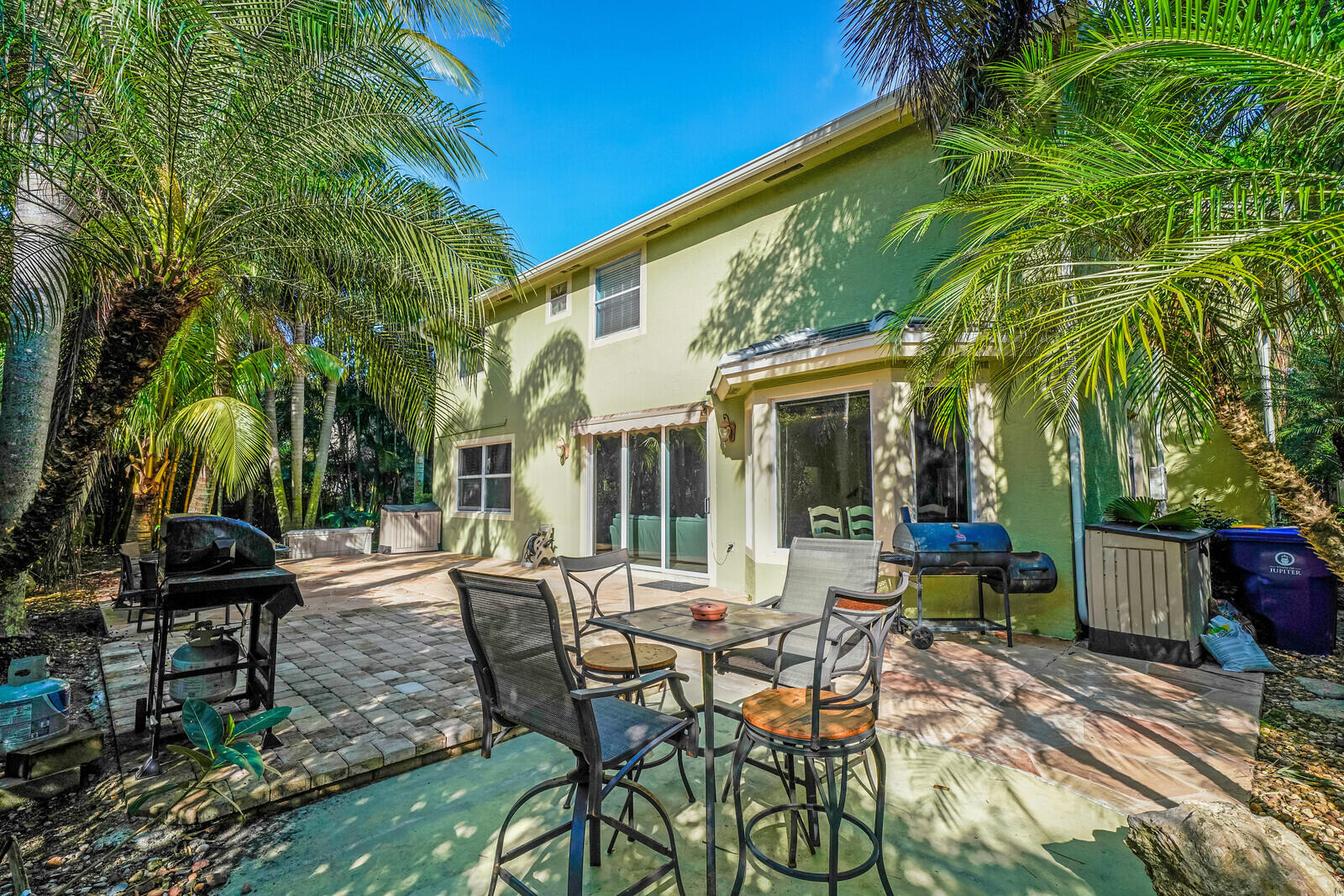 202 Anhinga Lane Jupiter, FL 33458 - Photo 40 of 40 a view of a patio with table and chairs potted plants and palm tree