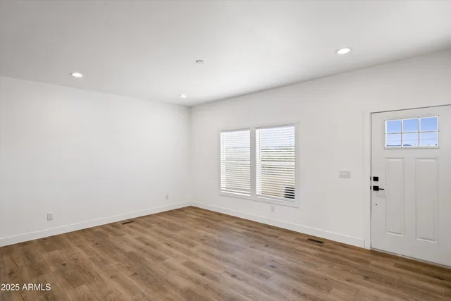 an empty room with wooden floor and windows