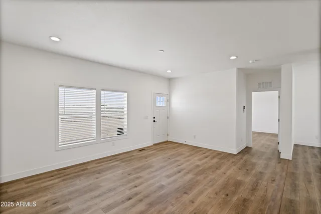 an empty room with wooden floor and windows