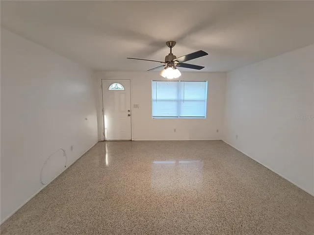 an empty room with a large window and a ceiling fan