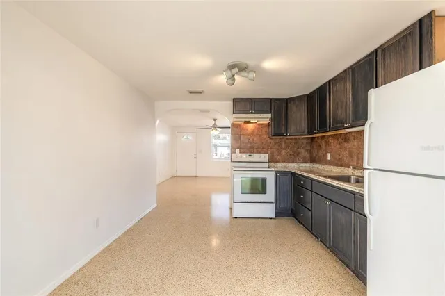 a kitchen with granite countertop a refrigerator and a stove top oven
