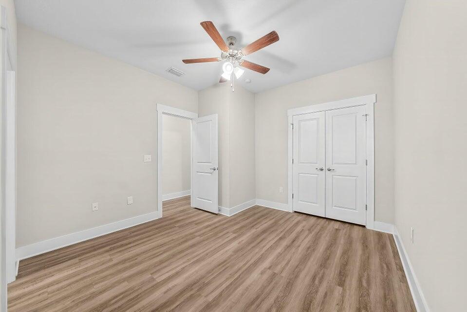 284 North Sand Palm Road, Unit VISTA Freeport, FL 32439 - Photo 18 of 27 an empty room with wooden floor ceiling fan and windows