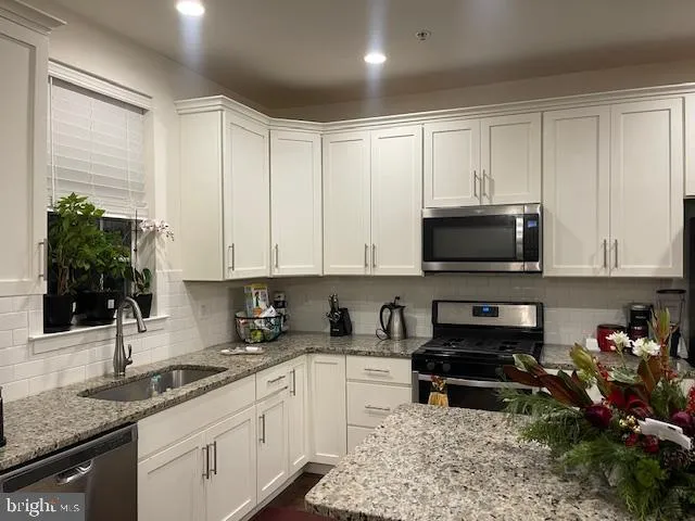 a kitchen with stainless steel appliances granite countertop a stove a sink a microwave and cabinets