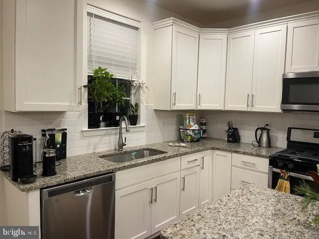 a kitchen with granite countertop a sink a stove and cabinets