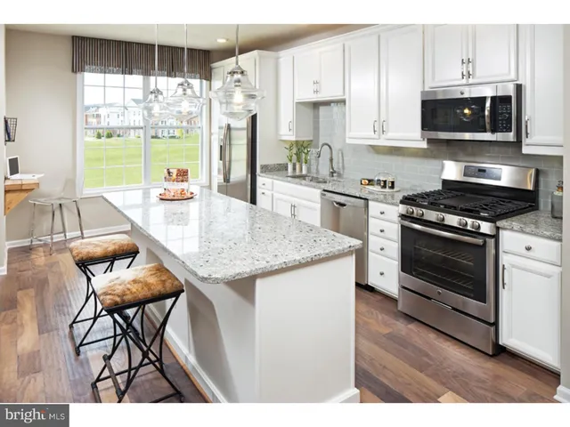 a kitchen with stainless steel appliances kitchen island granite countertop a stove a sink and a microwave