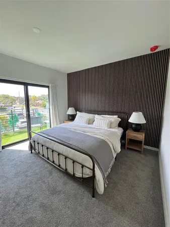 a bedroom with a bed a couch and a flat tv screen on the dresser