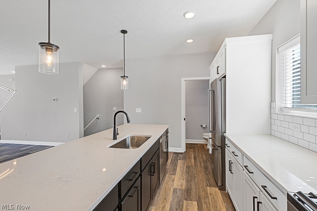 3601 Bailey Avenue Cleveland, OH 44113 - Photo 7 of 22 Kitchen with white cabinetry, decorative light fixtures, light stone countertops, sink, and dark wood-type flooring