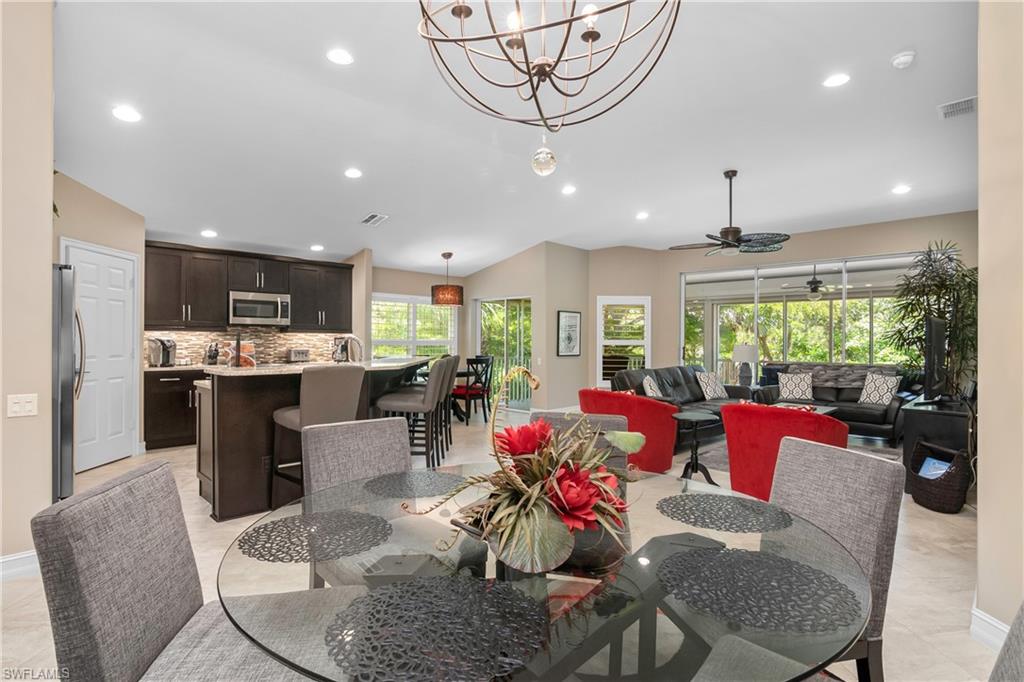 867 Carrick Bend Circle, Unit 2103 Naples, FL 34110 - Photo 13 of 32 a view of a dining room with furniture a chandelier and wooden floor