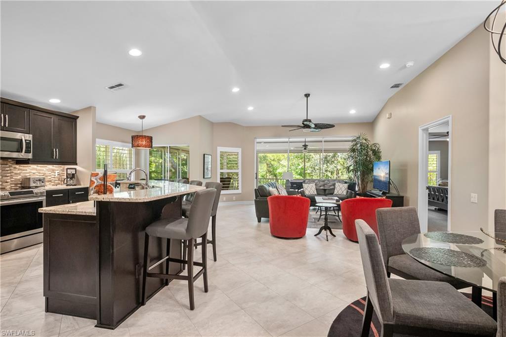 867 Carrick Bend Circle, Unit 2103 Naples, FL 34110 - Photo 3 of 32 a kitchen with stainless steel appliances granite countertop a stove top oven a sink dishwasher a dining table and chairs with wooden floor