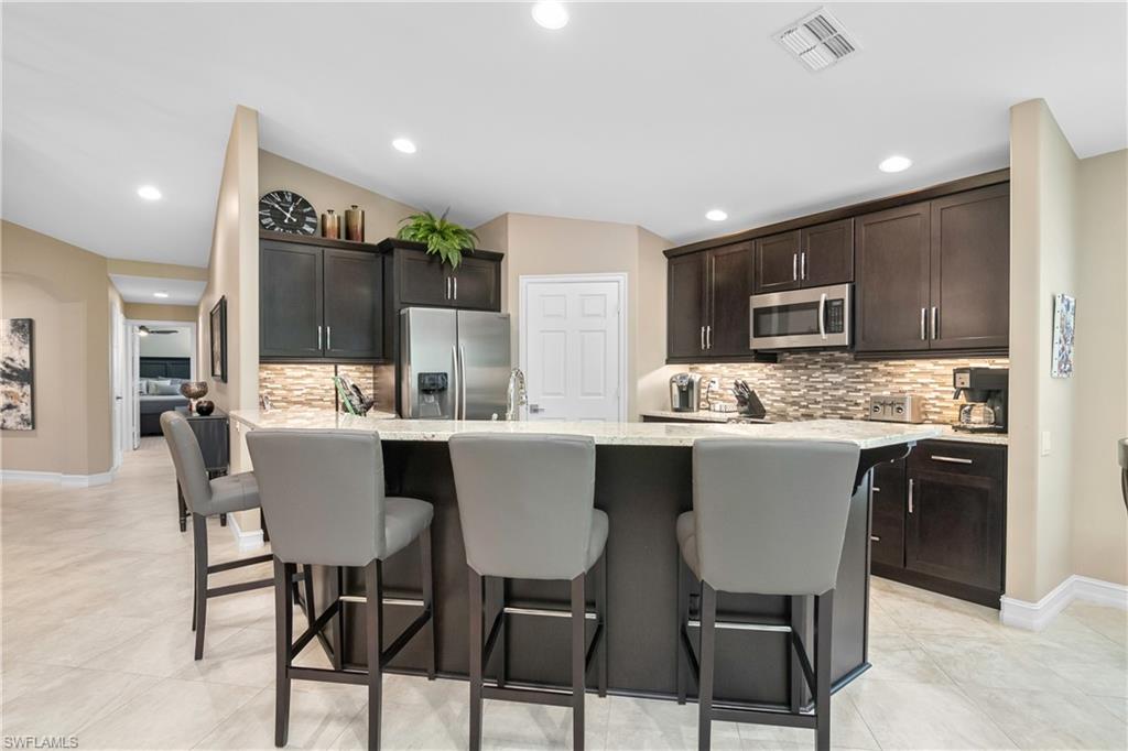 867 Carrick Bend Circle, Unit 2103 Naples, FL 34110 - Photo 7 of 32 a kitchen with kitchen island granite countertop wooden cabinets and stainless steel appliances