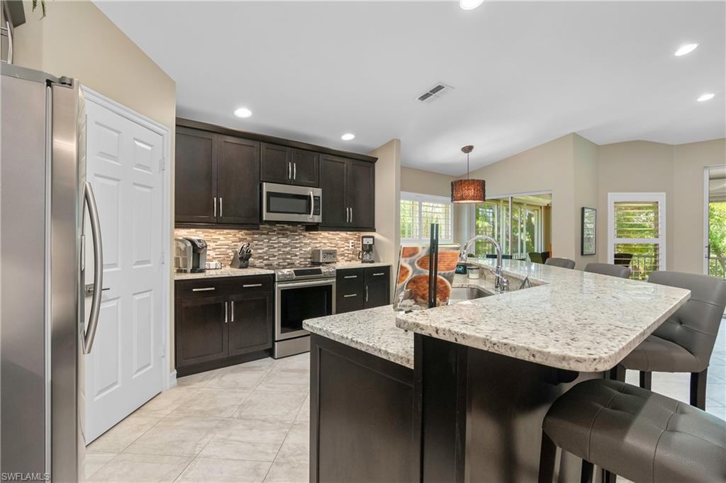 867 Carrick Bend Circle, Unit 2103 Naples, FL 34110 - Photo 9 of 32 a kitchen with stainless steel appliances granite countertop a stove refrigerator sink and cabinets