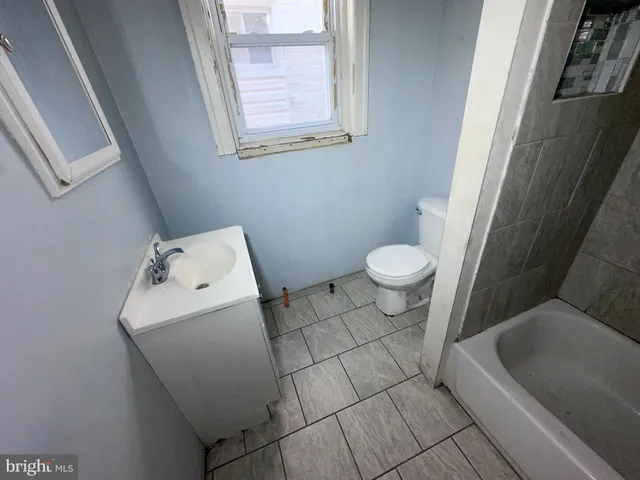 a view of an empty room with wooden floor and fan