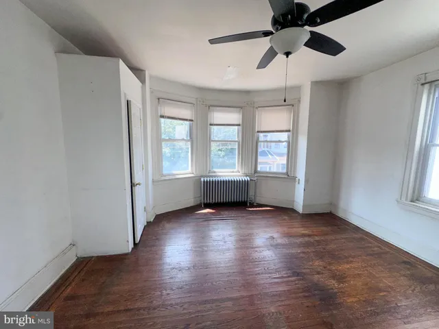 a view of empty room with wooden floor and ceiling fan