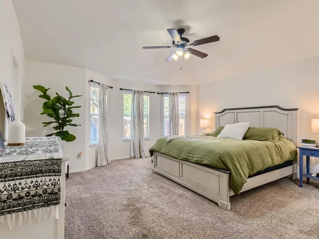 a spacious bedroom with a bed a dresser with wooden floor