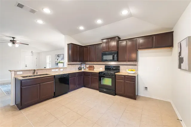 a large kitchen with stainless steel appliances granite countertop a sink dishwasher stove and refrigerator