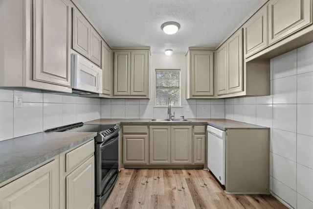 a kitchen with stainless steel appliances granite countertop a sink a stove and cabinets