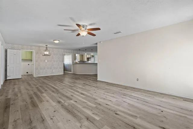 a view of a room with wooden floor and a ceiling fan