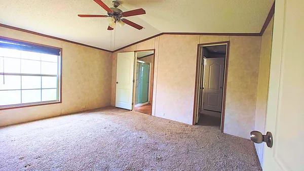 an empty room with windows and ceiling fan