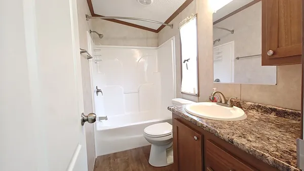 a bathroom with a granite countertop sink toilet a mirror and shower