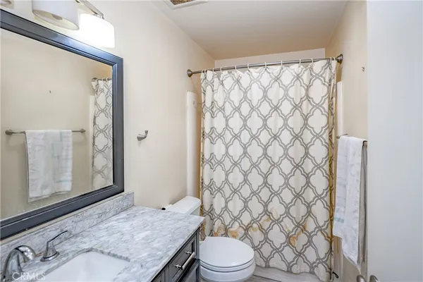 a bathroom with a granite countertop toilet and a shower curtain
