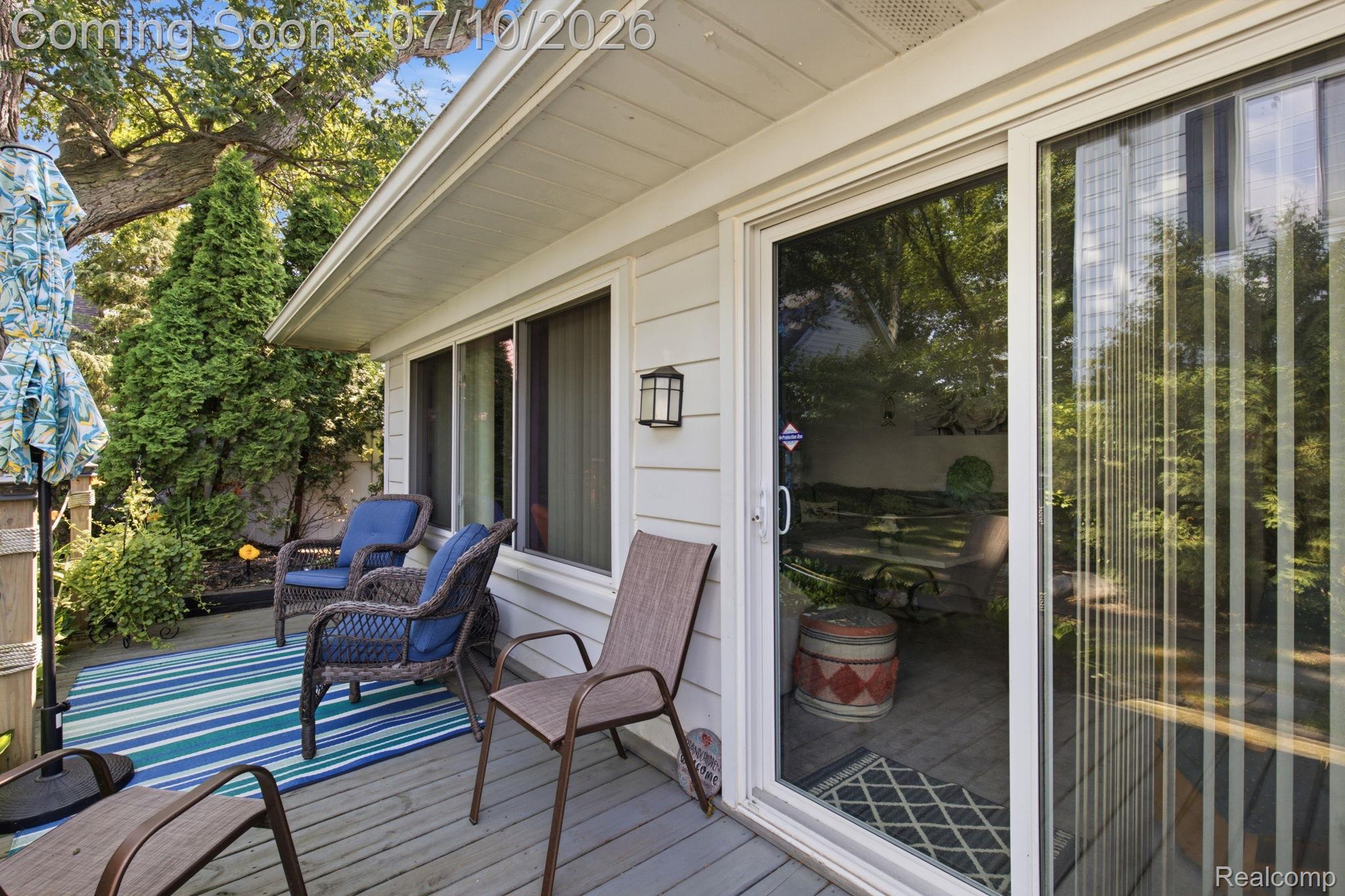 1501 River Road, Unit 301 St. Clair, MI 48079 - Photo 30 of 32 Private patio featuring wood-finish decking, direct access via sliding glass doors, and mature surrounding greenery
