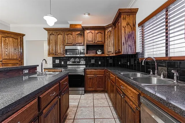 a kitchen with stainless steel appliances granite countertop a sink a stove counter space and cabinets
