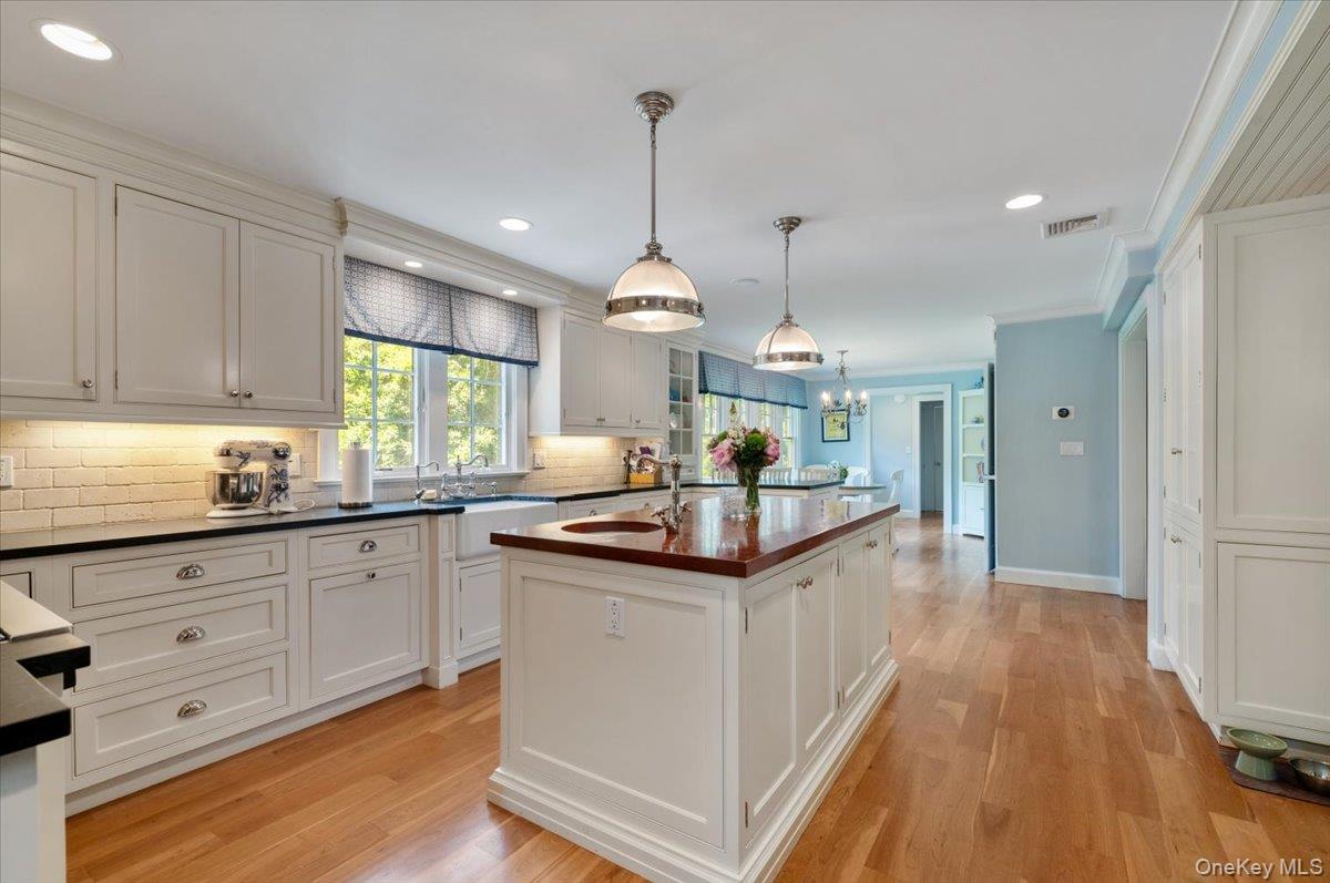 5 Fox Hunt Court Cold Spring Harbor, NY 11724 - Photo 12 of 42 Open concept kitchen featuring white cabinetry, wood-finish flooring, a butcher block island, and a farmhouse sink