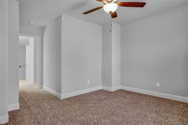 an empty room with a ceiling fan and carpet