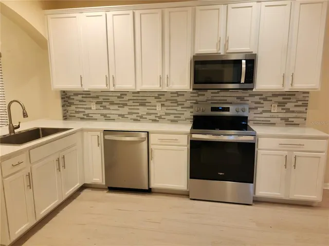 a kitchen with stainless steel appliances white cabinets and a stove top oven