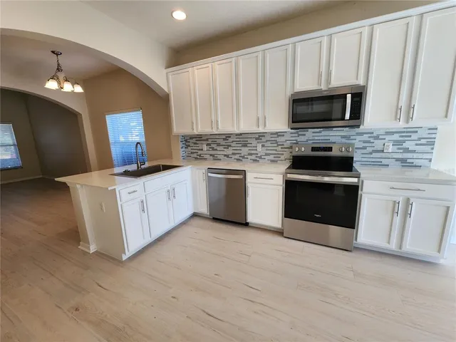 a kitchen with stainless steel appliances granite countertop a stove top oven a sink dishwasher and a microwave oven on the blue kitchen countertops