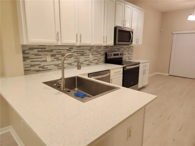 a kitchen with granite countertop a sink a stove top oven and white cabinets