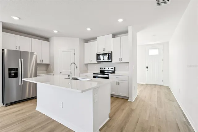 a kitchen with white cabinets and stainless steel appliances