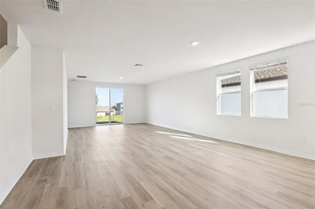 a view of empty room with wooden floor and window