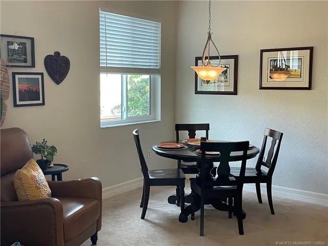 a living room with stainless steel appliances furniture a rug and a kitchen view