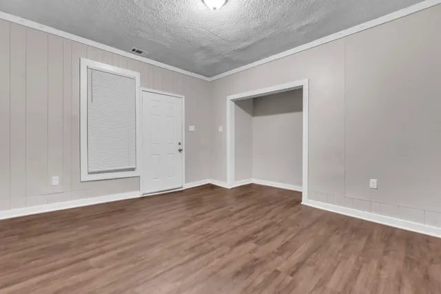 a view of an empty room with wooden floor and closet