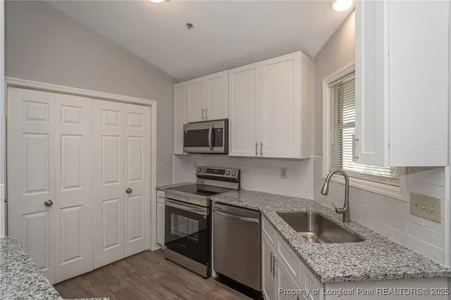 a kitchen with granite countertop white cabinets and stainless steel appliances
