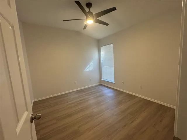 a view of empty room with wooden floor and fan