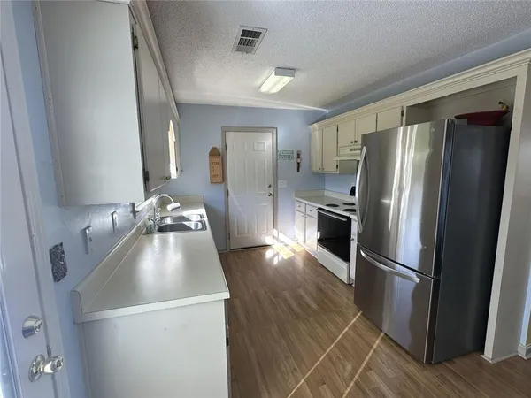 a kitchen with a refrigerator sink and wooden floor